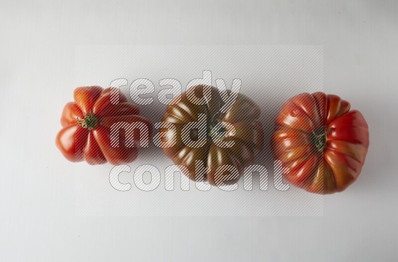 three heirloom tomatoes topview on a white background