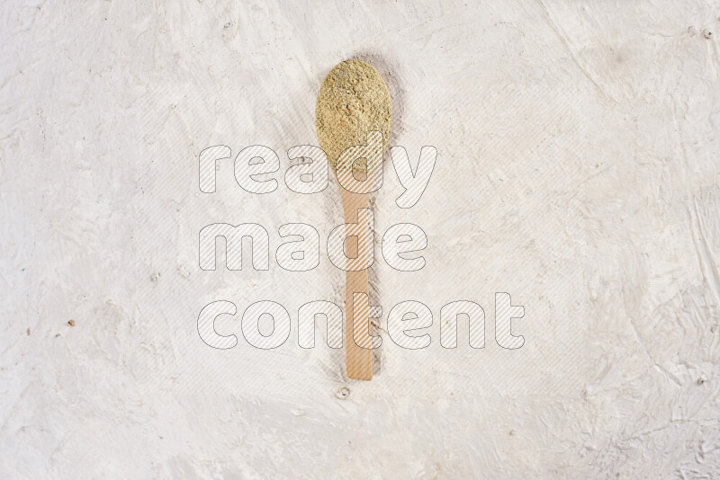 A wooden spoon full of ground ginger powder on white background