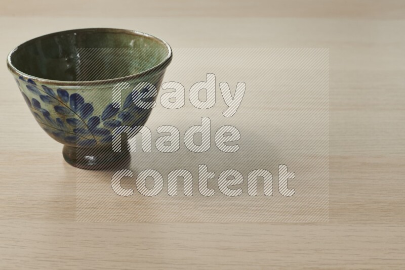 A decorative pottery bowl on light wooden background