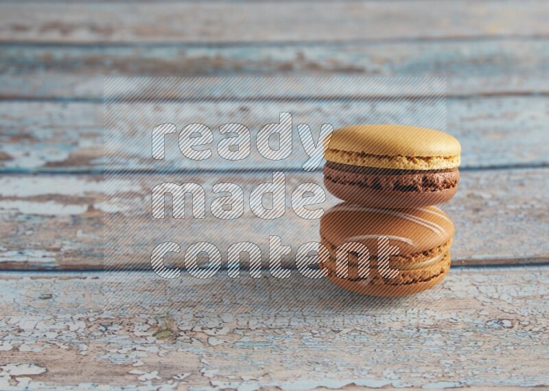 45º Shot of of two assorted Brown Irish Cream, and Yellow, and Brown Chai Latte macarons  on light blue background