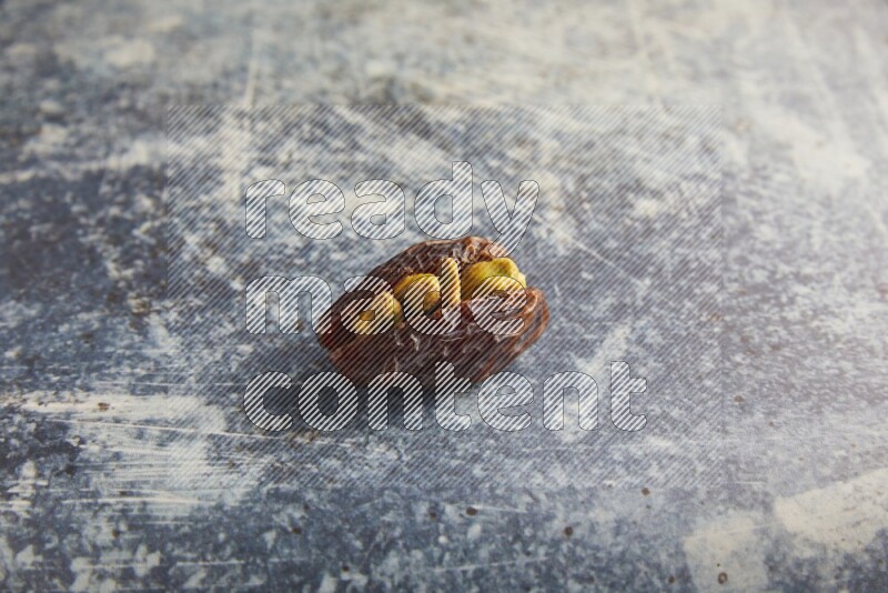 pistachios stuffed madjoul date on a rustic blue background