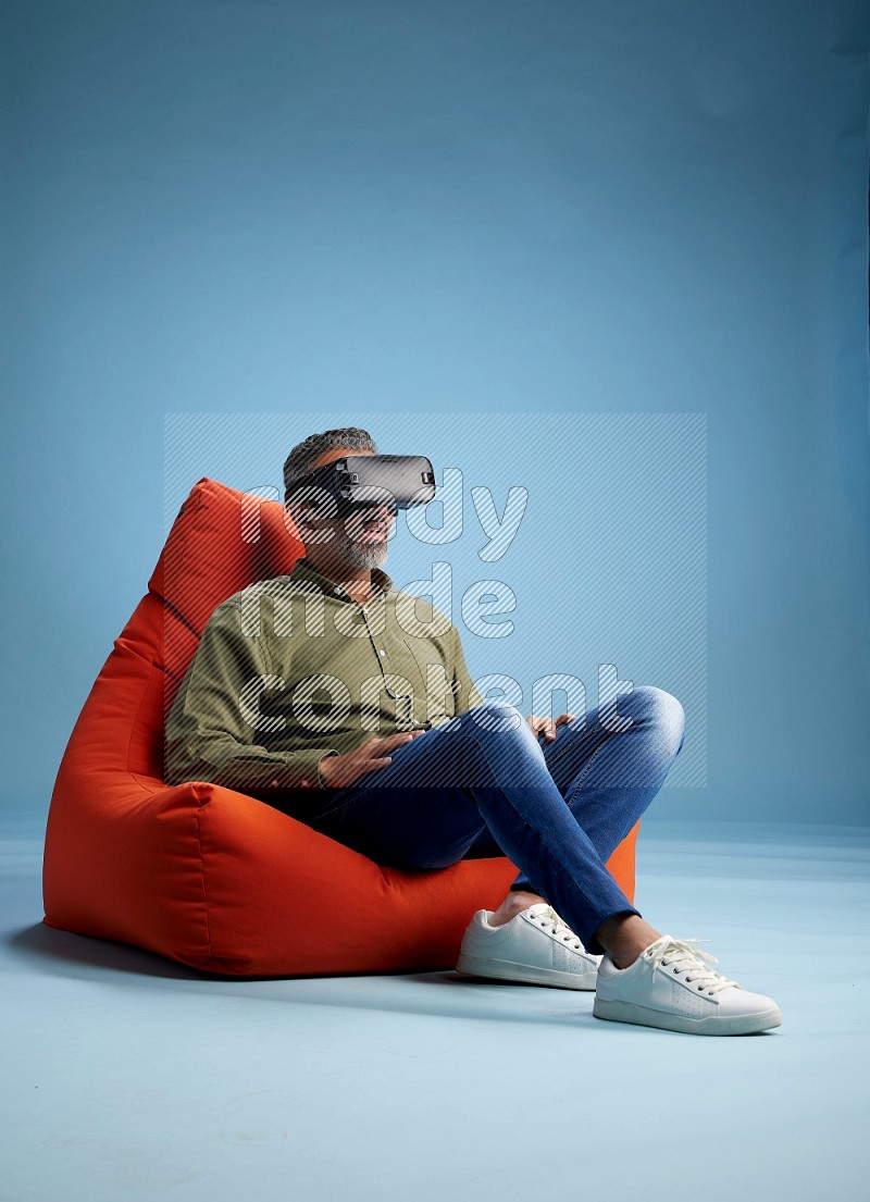 A man sitting on an orange beanbag and gaming with VR
