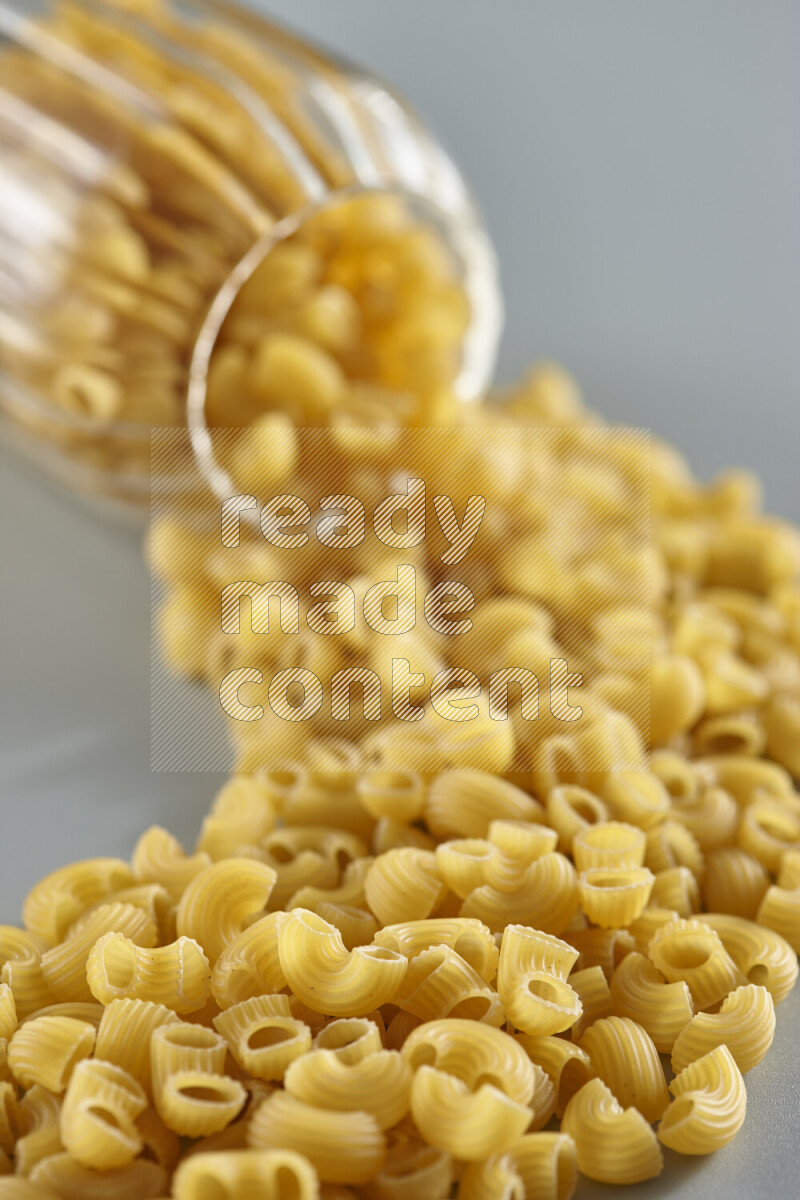 Flipped jar full of raw pasta on light blue background