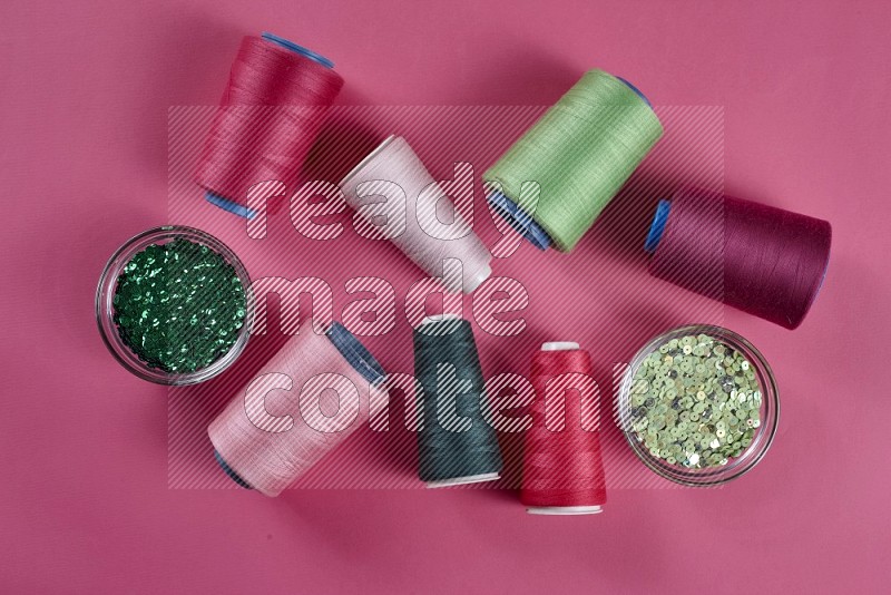 A green and pink collection of sewing and tailoring tools arranged on a pink background