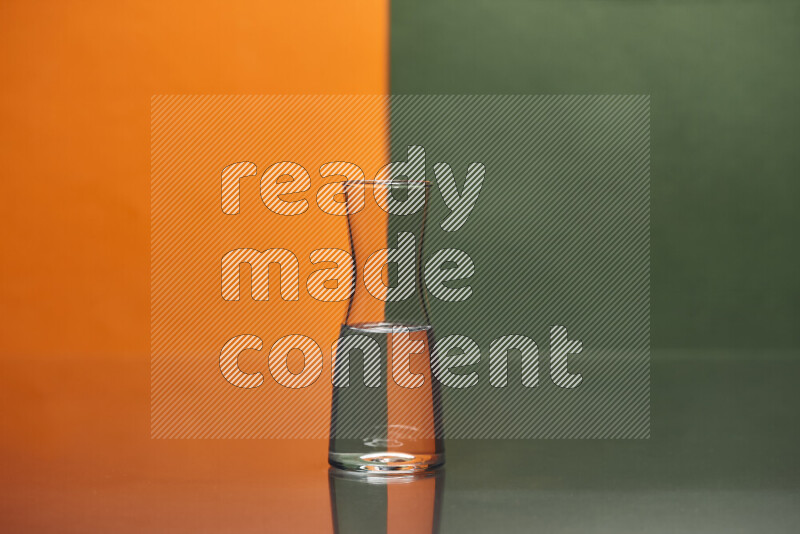 The image features a clear glassware filled with water, set against orange and dark green background