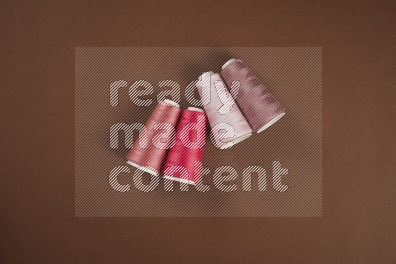 مجموعة من أدوات الخياطة والتفصيل زهرية اللون على خلفية بنية