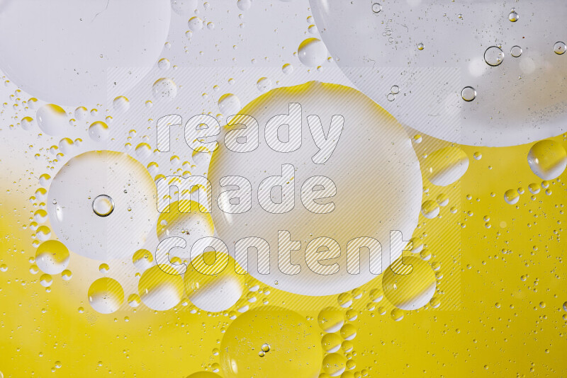 Close-ups of abstract oil bubbles on water surface in shades of white and yellow