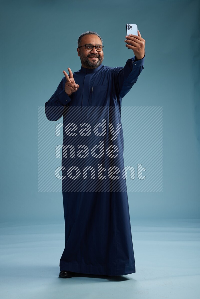 Saudi Man without shimag Standing taking selfie on blue background