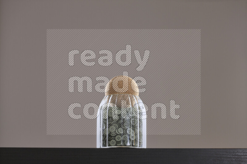 أزرار متنوعة في وعاء زجاجي علي خلفية سوداء