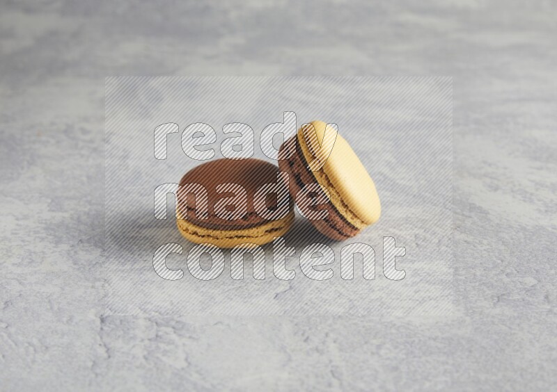 45º Shot of two Yellow and Brown Chai Latte macarons r on white  marble background