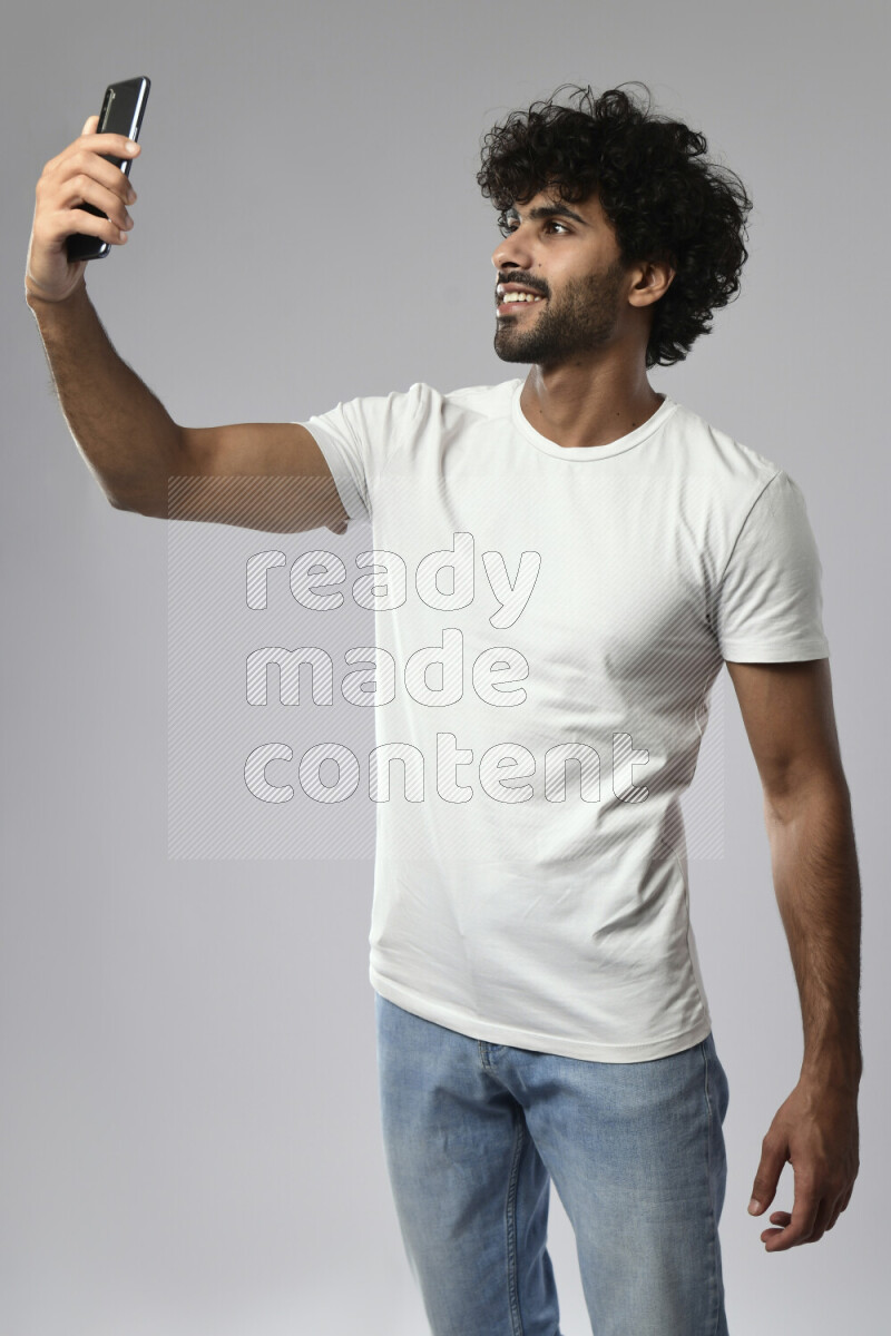 A man wearing casual standing and taking a selfie on white background