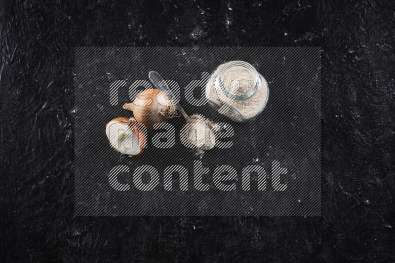 A glass jar full of onion powder on black background