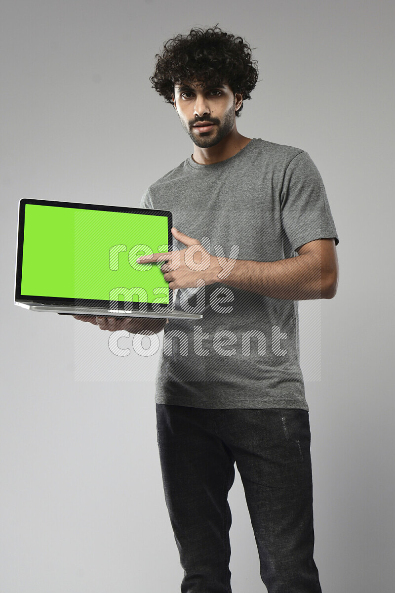 A man wearing casual standing and showing a laptop screen on white background