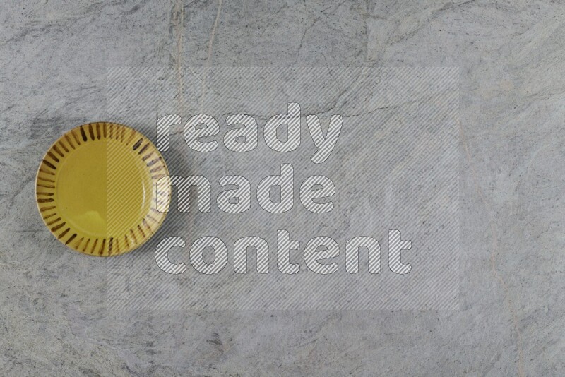 A multicolored pottery plate on grey marble background