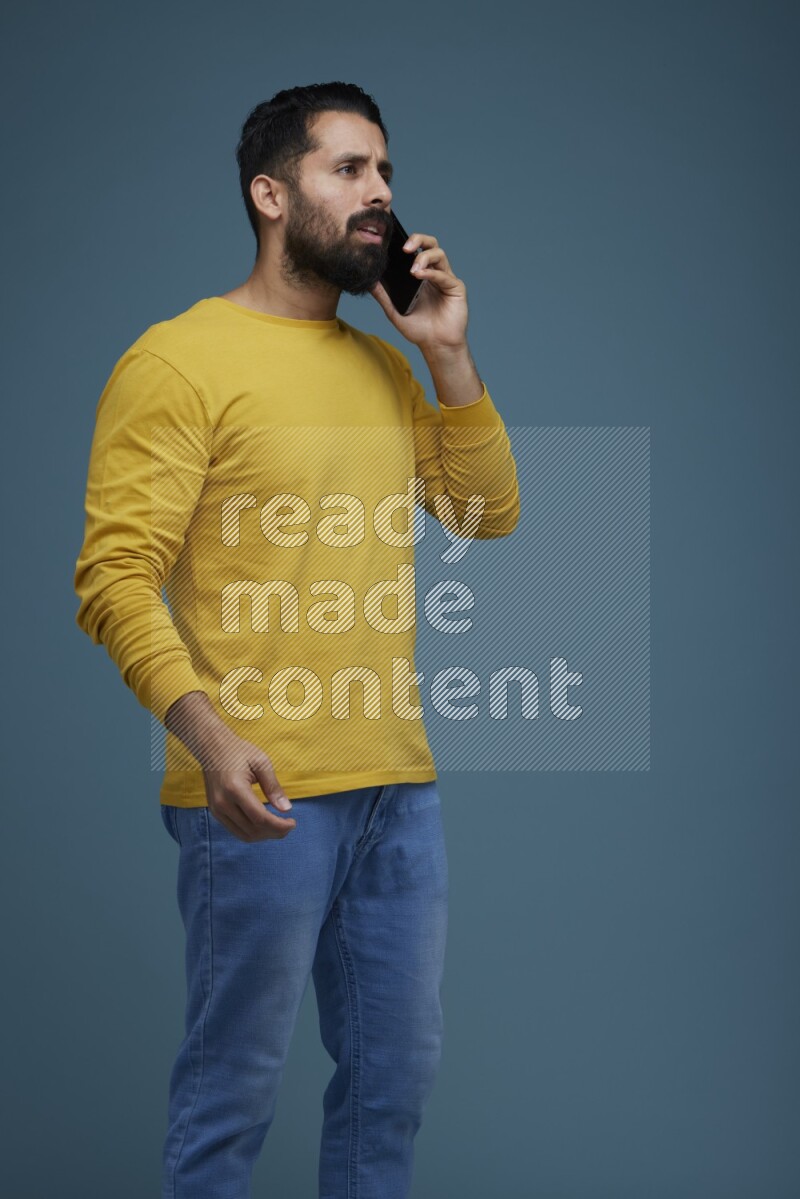 A man having a calling in a blue background wearing a yellow shirt