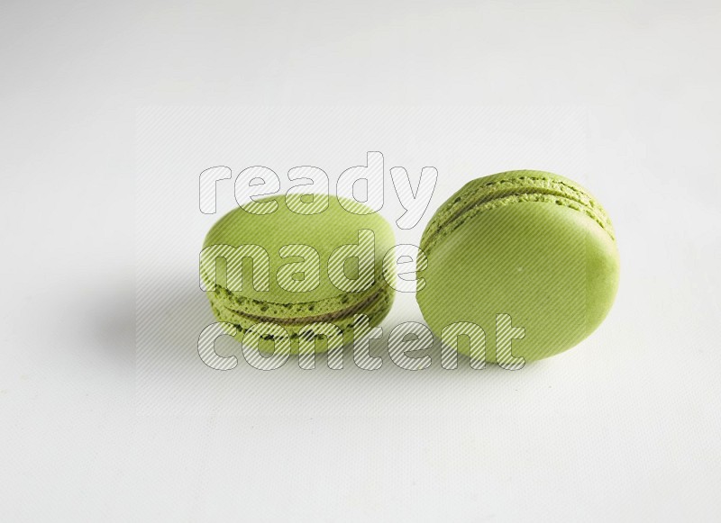 45º Shot of two Green Pistachio macarons on white background