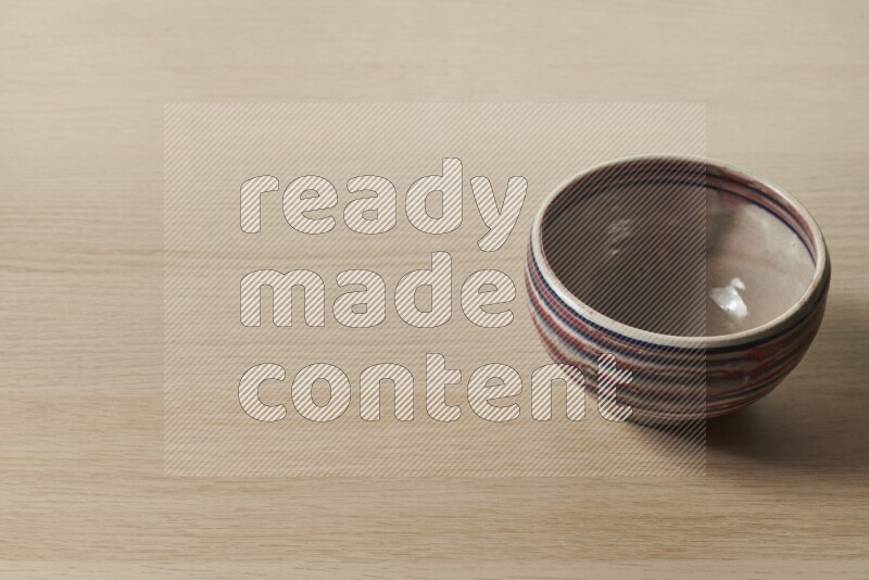 A multicolored pottery bowl on light wooden background