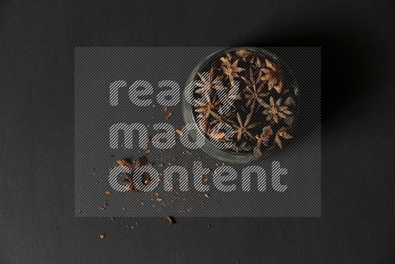 Star Anise in a black bowl with sprinkled anise on black flooring