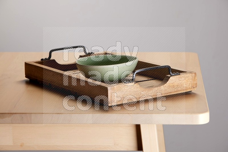 green bowl on a light colored rectangular wooden tray with handles