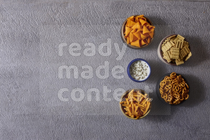 وجبات خفيفة متنوعة في أوعية فخارية على خلفية رمادية