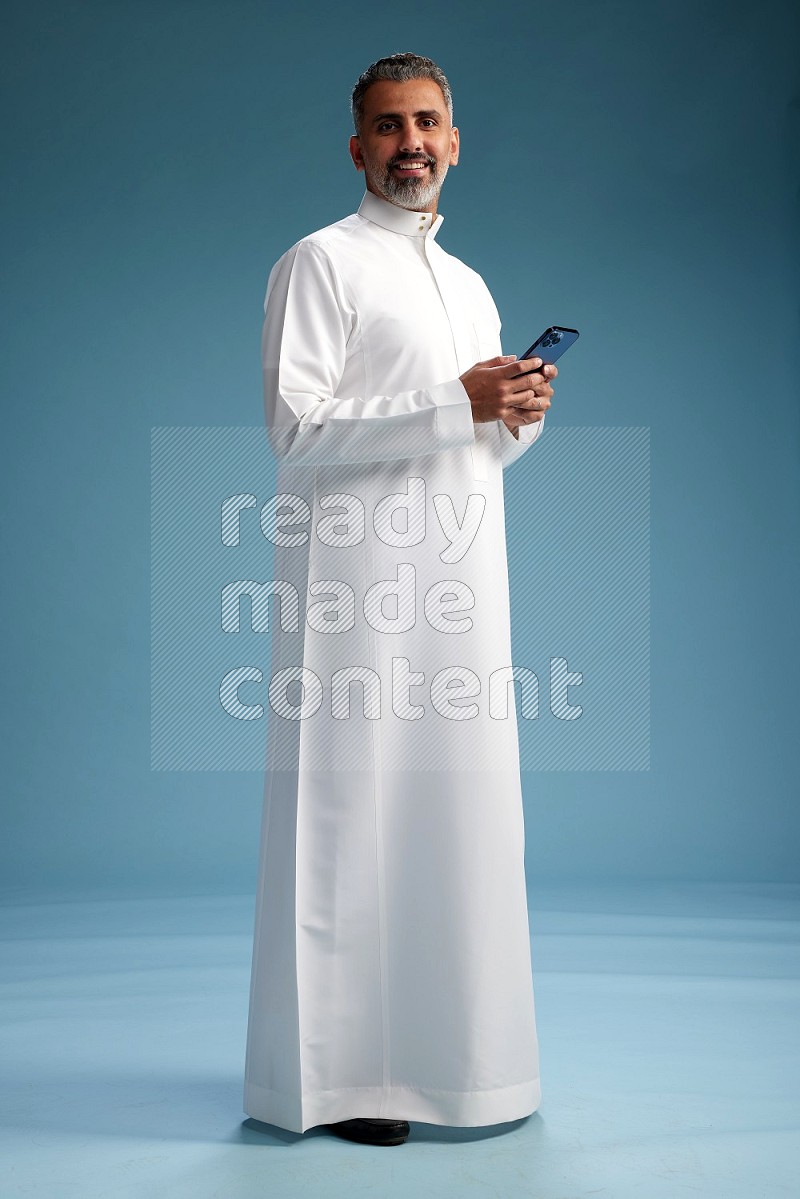 Saudi man waring thob texting on blue background