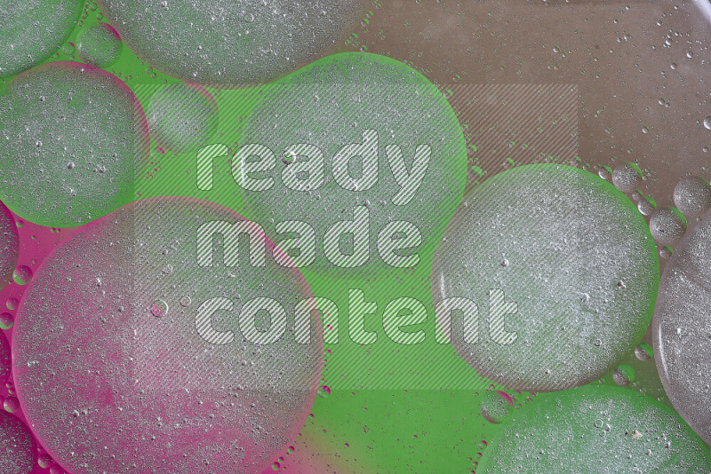 لقطات مقربة لفقاعات من الزيت على سطح الماء باللون البني والأخضر والوردي