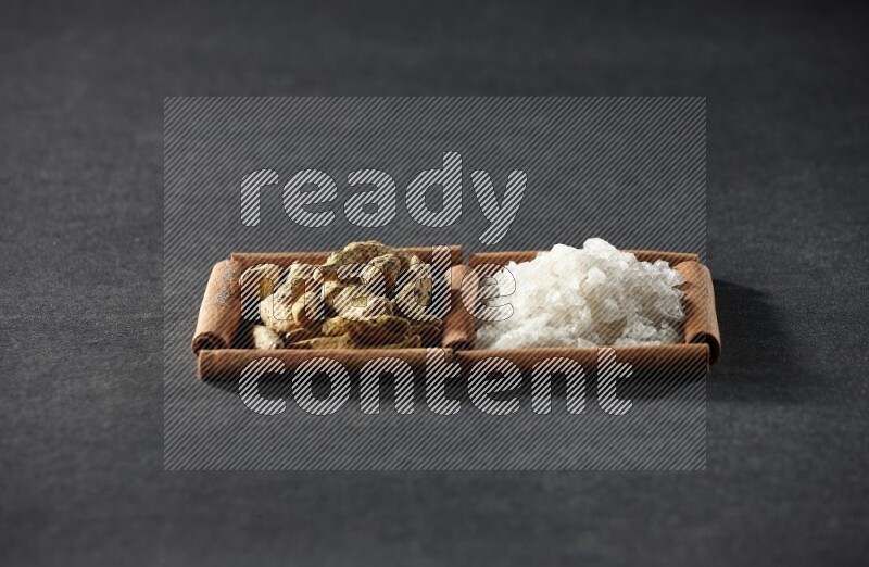 2 squares of cinnamon sticks full of white salt and turmeric fingers on black flooring