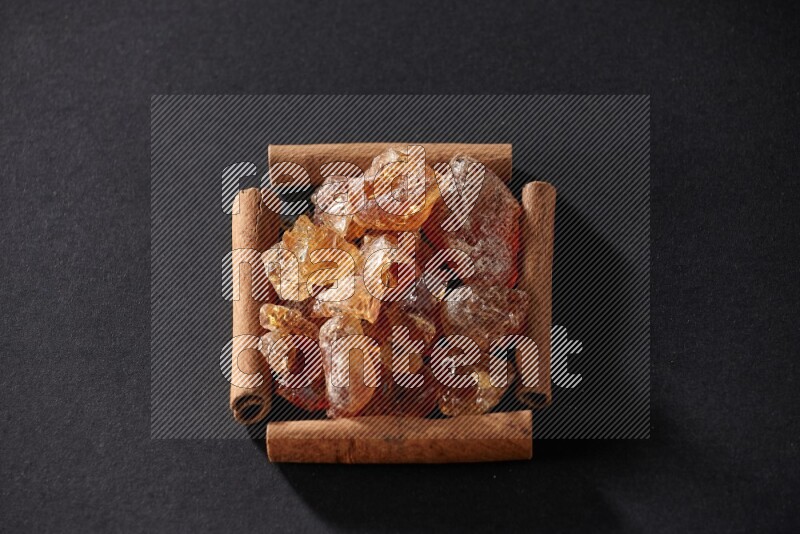 A single square of cinnamon sticks full of Arabic gum on black flooring