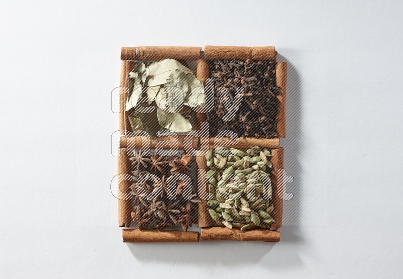 4 squares of cinnamon sticks full of cardamom, star anise, cloves and bay laurel leaves on white flooring
