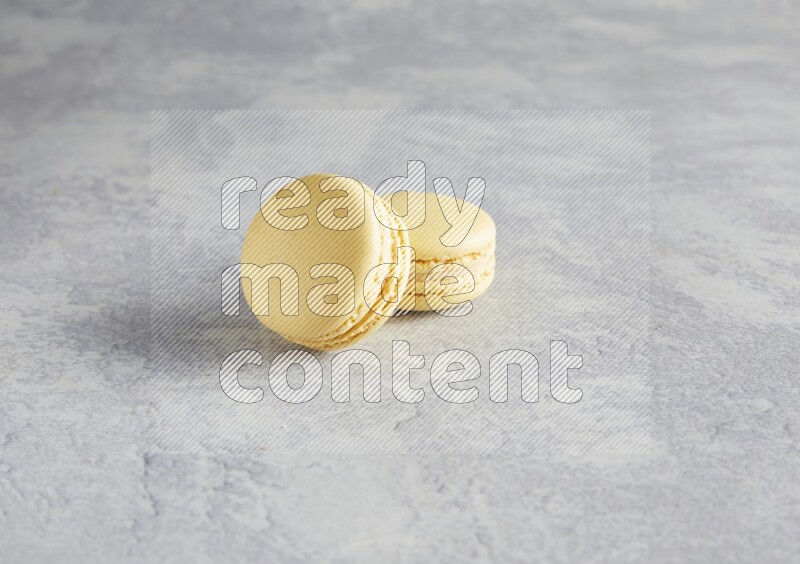 45º Shot of two Yellow Vanilla macarons  on white  marble background