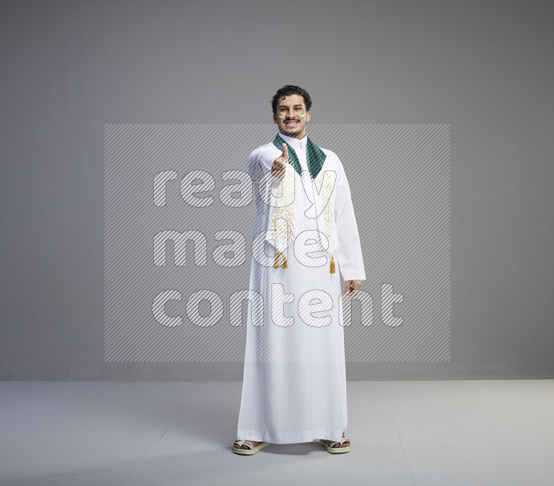 رجل سعودي يرتدي ثوب ابيض يضع شال مكتوب عليه المملكة العربية السعودية حول رقبته