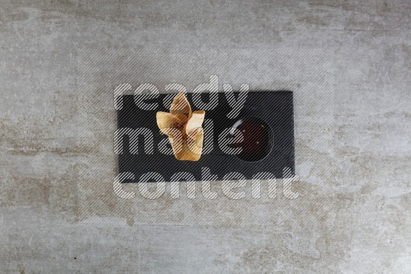 wonton cups with soy sauce ramkin on rectangle slate on grey textured counter top