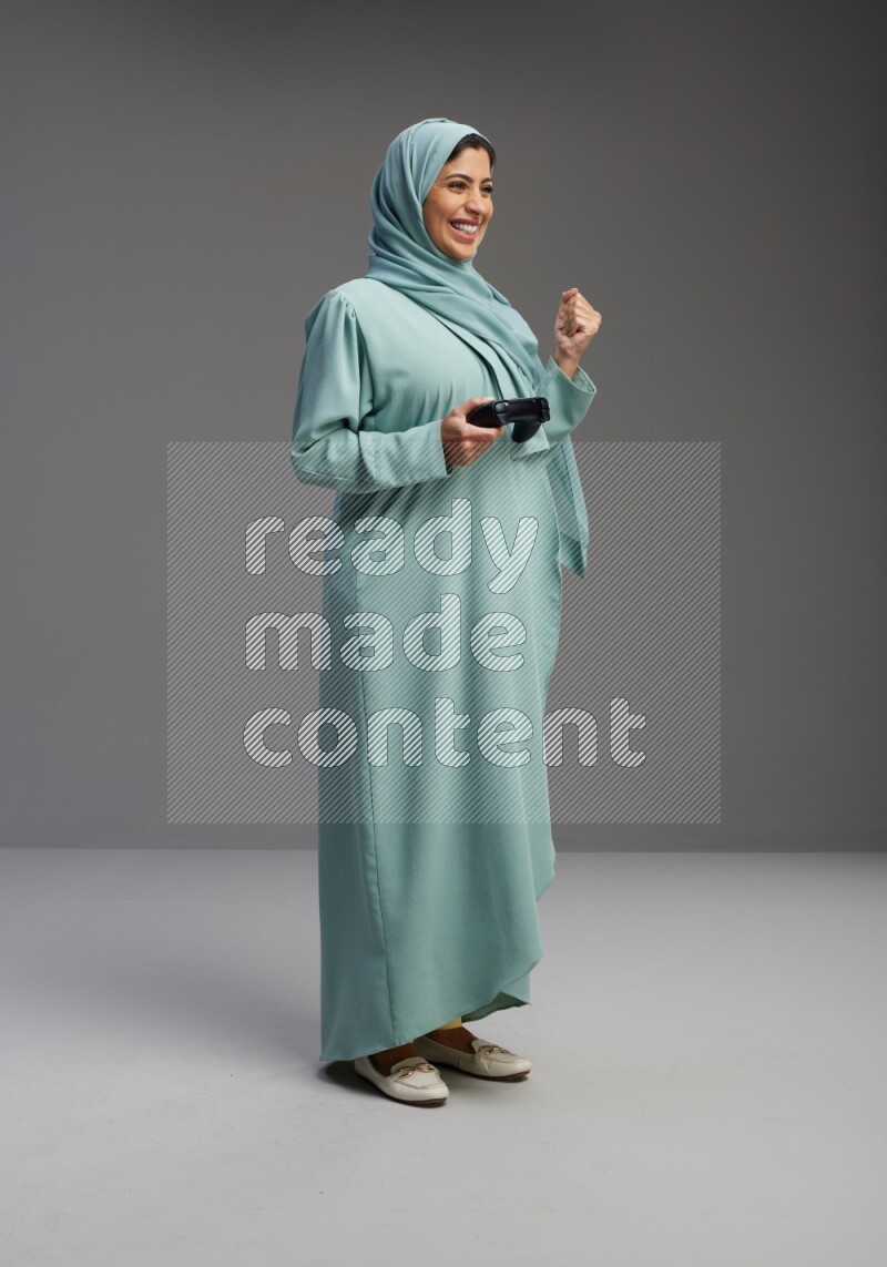Saudi Woman wearing Abaya standing Playing Games on Gray background