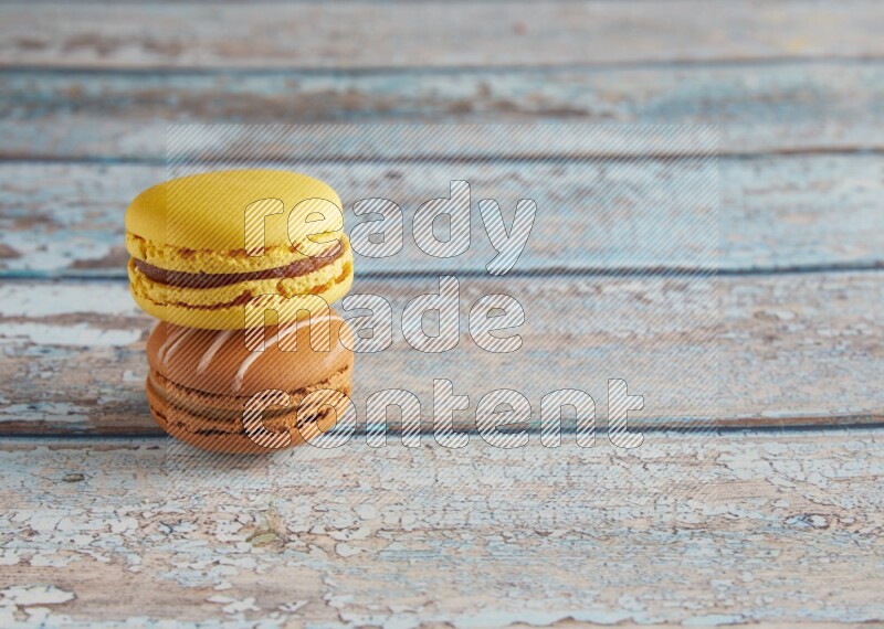 45º Shot of of two assorted Brown Irish Cream, and Yellow Lemon macarons on light blue background