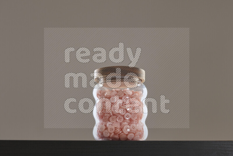 أزرار متنوعة في وعاء زجاجي علي خلفية سوداء