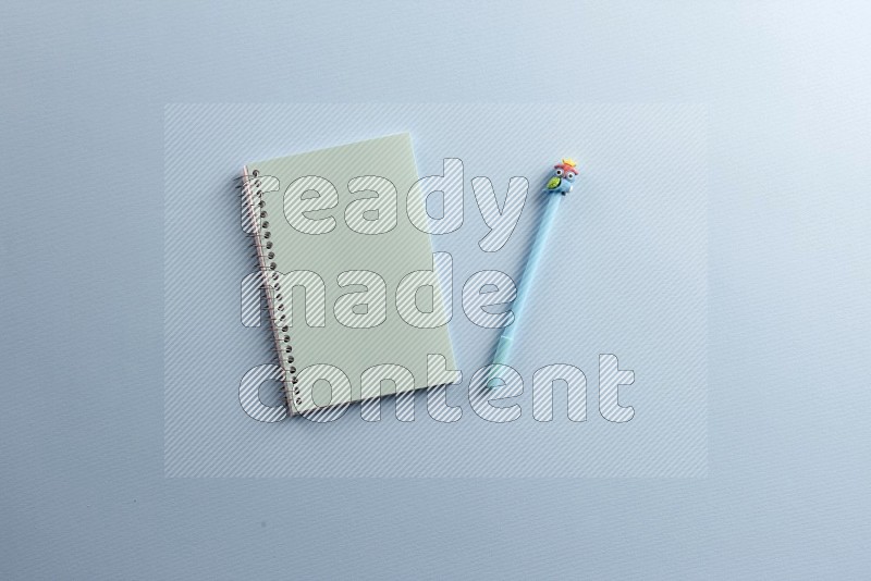 A blue notebook with different school supplies on blue background