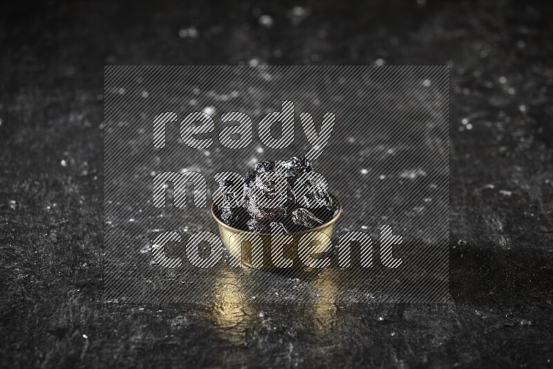 Dried fruits in a metal bowl in a dark setup