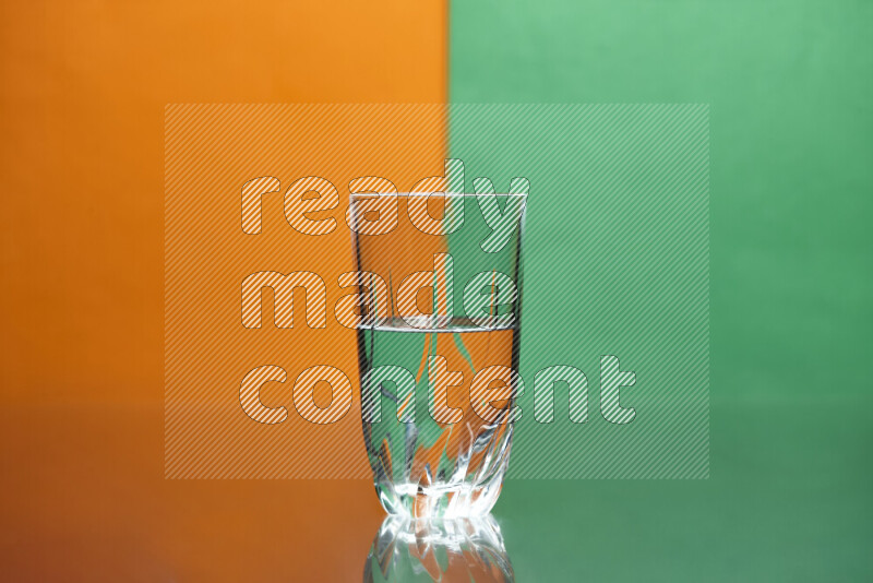 The image features a clear glassware filled with water, set against orange and green background