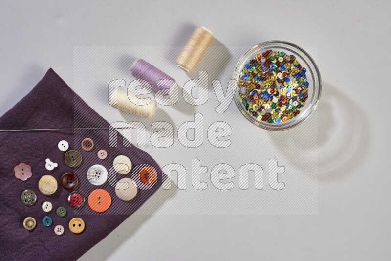 Multicolored fabrics with sewing supplies on grey background