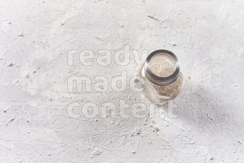 A glass jar full of onion powder on white background