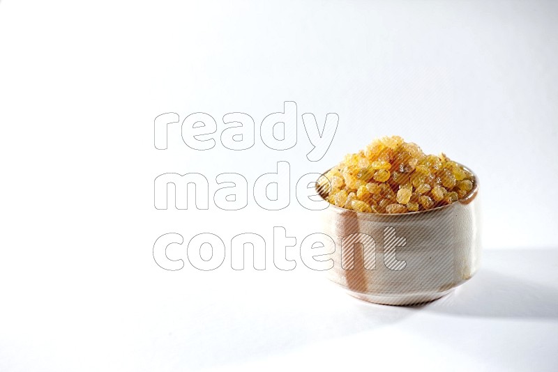 A beige ceramic bowl full of raisins on a white background in different angles