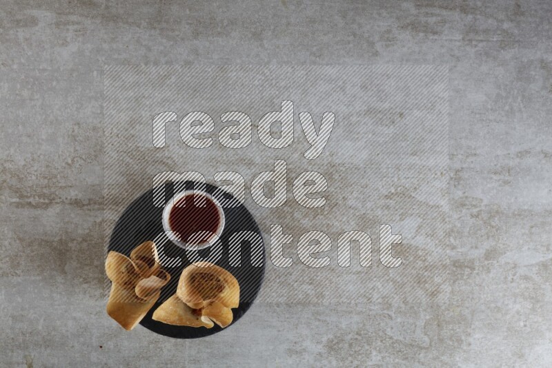 wonton cups with soy sauce ramkin on circle slate on grey textured counter top