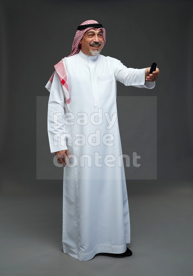 Saudi man with shomag Standing holding car key on gray background
