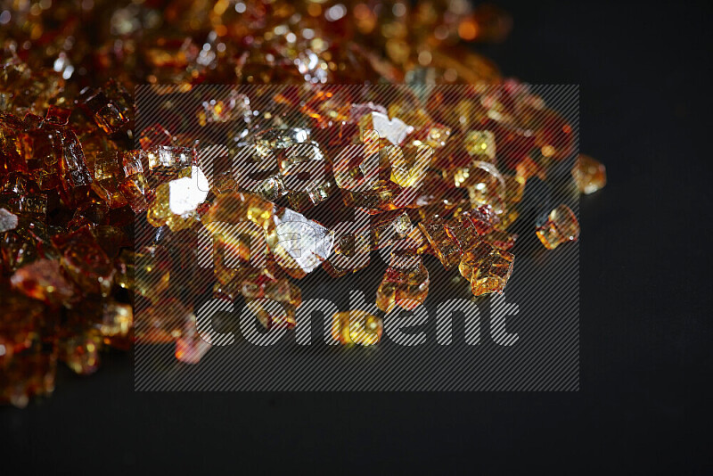 Transparent orange fragments of glass scattered on a black background