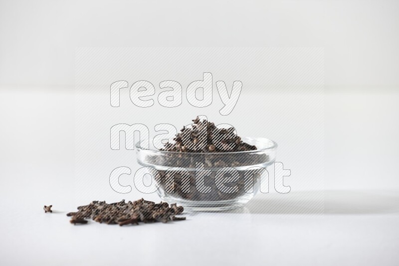 A glass bowl full of cloves on a white flooring