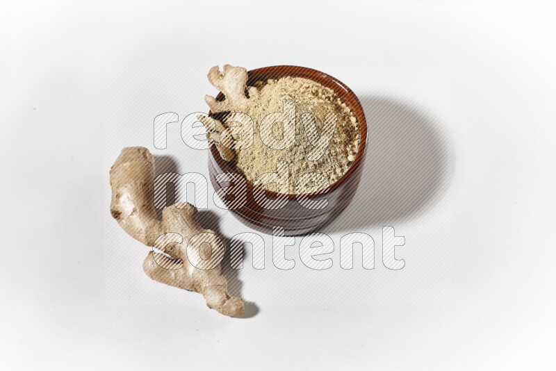 A brown pottery bowl full of ground ginger powder on white background