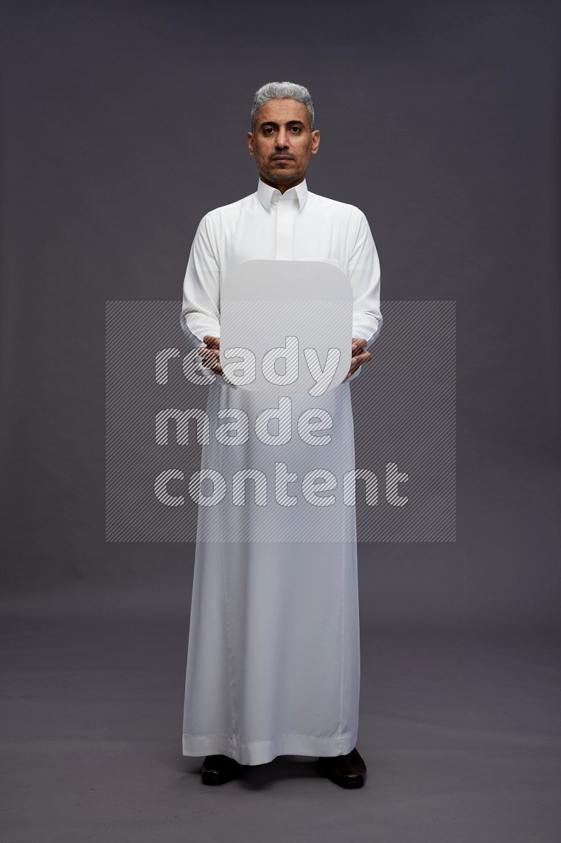 Saudi man wearing thob standing holding social media sign on gray background