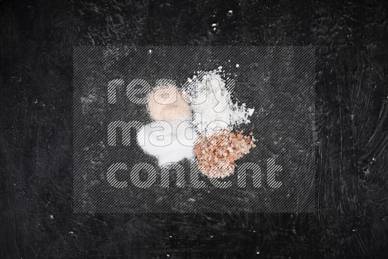 4 glass jars filled with table salt, coarse sea salt, fine himalayan salt and coarse himalayan salt on black background