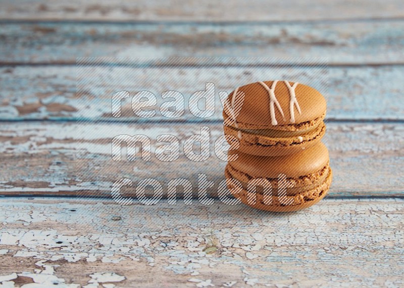 45º Shot of of two assorted Brown Irish Cream, and Brown Maple Taffy macarons  on light blue background