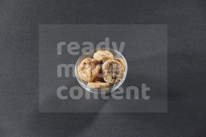 A glass bowl full of dried figs on a black background in different angles